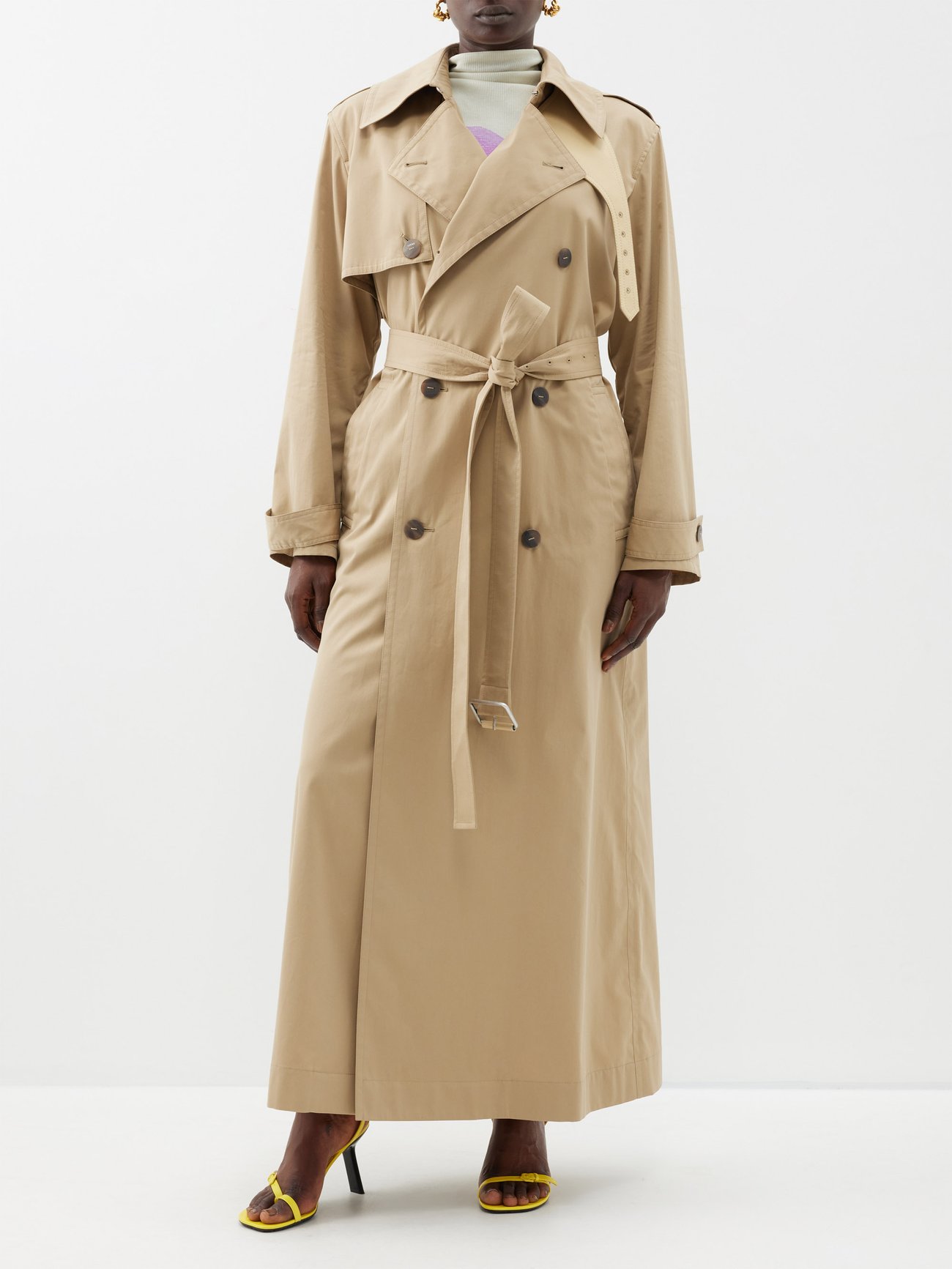 Tailored to a floor-length hem, LOEWE’s beige gabardine trench coat spotlights a storm flap, sharp notch lapels and is cinched at the waist with a buckled belt.
