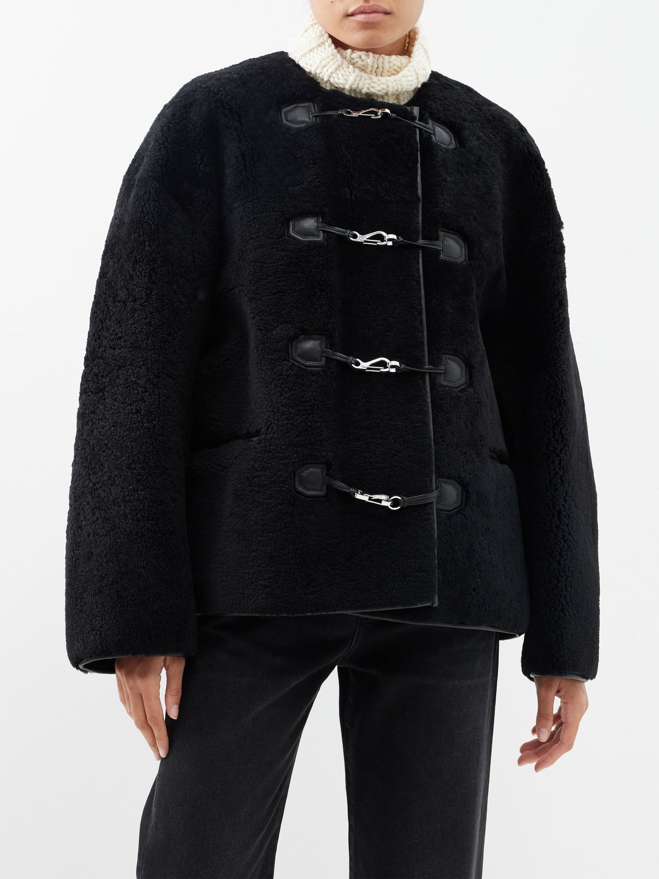 Trending Winter Coats 2023 2024 - Silver carabiner clasps bring a contemporary verve to Toteme's boxy black jacket, crafted from luxuriously plush teddy shearling and finished with leather trims.