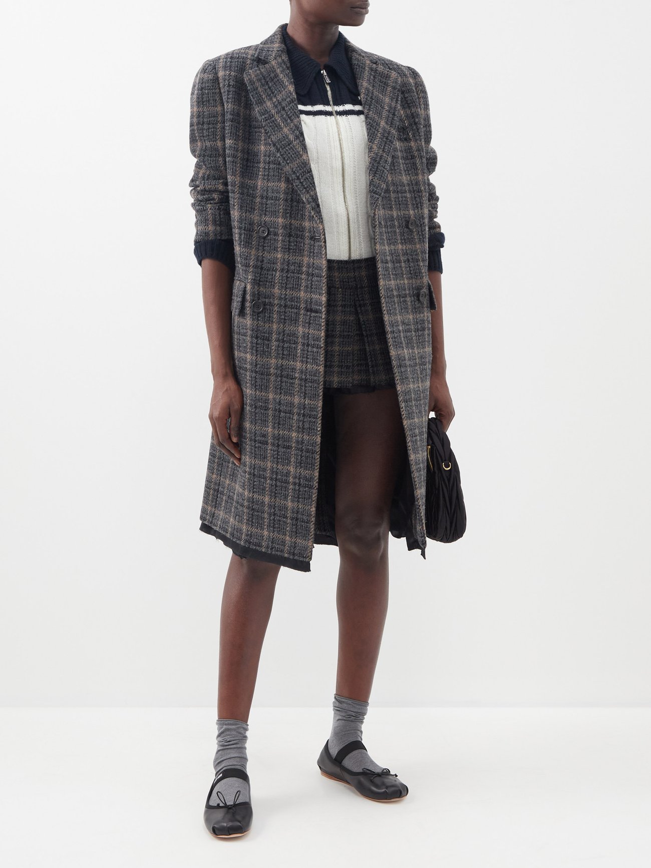 Miu Miu's grey coat features in Look 26 of the AW22 runway, and is tailored to the collection's boxy oversized fit from raw-edged tartan wool. It comes in a grey check and is double breasted with a button fastening. It has notch lapels, cropped sleeves, flap pockets, and a back vent. Wear with the labels mirco mini pleated skirt in the same fabric to lean into AW22s punk preppy trend. 